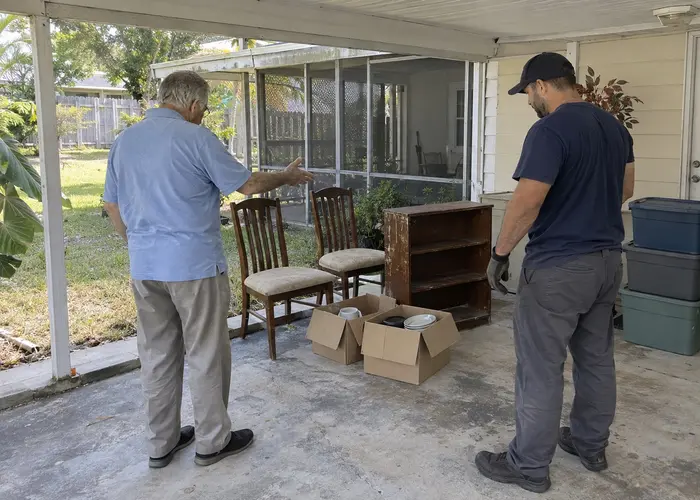 Two people reviewing chairs, shelving and boxes on a covered patio