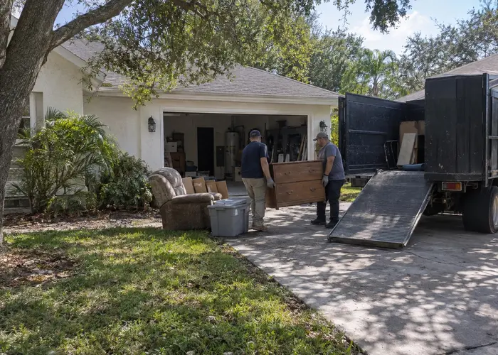 Two people carrying a dresser toward an open truck